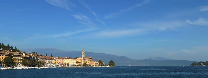 Trip Adria beliebte Urlaubsziele am Gardasee -  Mit einer Fläche von 370 km² ist der Gardasee der größte See Italiens. Es liegt am Fuße der Alpen und erstreckt sich über drei Staaten: Lombardei, Venetien und Trentino. Die maximale Tiefe des Sees beträgt 346 m, er hat eine längliche Form und sein nördliches Ende ist sehr schmal. Dort ist der See von den Bergen der Gruppo di Baldo umgeben. Du trittst aus deinem gemütlichen Hotelzimmer und es begrüßt dich die warme italienische Sonne. Du blickst auf den atemberaubenden Gardasee, der in zahlreichen Blautönen schimmert - von tiefem Dunkelblau bis zu funkelndem Türkis. Majestätische Berge umgeben dich, während die Brise sanft deine Haut streichelt und der Duft von blühenden Zitronenbäumen deine Nase kitzelt. Du schlenderst die malerischen, engen Gassen entlang, vorbei an farbenfrohen, blumengeschmückten Häusern. Vereinzelt unterbricht das fröhliche Lachen der Einheimischen die friedvolle Stille. Du fühlst dich wie in einem Traum, der nicht enden will. Jeder Schritt führt dich zu neuen Entdeckungen und Abenteuern. Du probierst die köstliche italienische Küche mit ihren frischen Zutaten und verführerischen Aromen. Die Sonne geht langsam unter und taucht den Himmel in ein leuchtendes Orange-rot - ein spektakulärer Anblick.